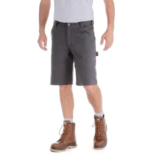 Mężczyzna ubrany w szare spodenki Carhartt Rigby Dungaree Short i brązowe skórzane buty robocze stoi na białym tle. Spodenki mają klasyczny krój z kieszeniami i są zestawione z jasnoszarą koszulką.