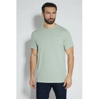 Mężczyzna w jasnozielonej koszulce z krótkim rękawem i kieszonką na piersi stoi na tle białej ściany. Koszulka ma małe logo Carhartt na kieszeni, a mężczyzna nosi ciemne spodnie.