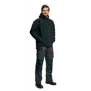 Mężczyzna ubrany w czarną kurtkę typu softshell i ciemne spodnie robocze stoi na białym tle. Kurtka ma pomarańczowe akcenty, a spodnie posiadają liczne kieszenie.