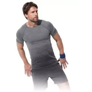 Mężczyzna w szarym, dopasowanym t-shircie i szortach pozuje na białym tle. Na nadgarstku ma niebieską opaskę sportową.